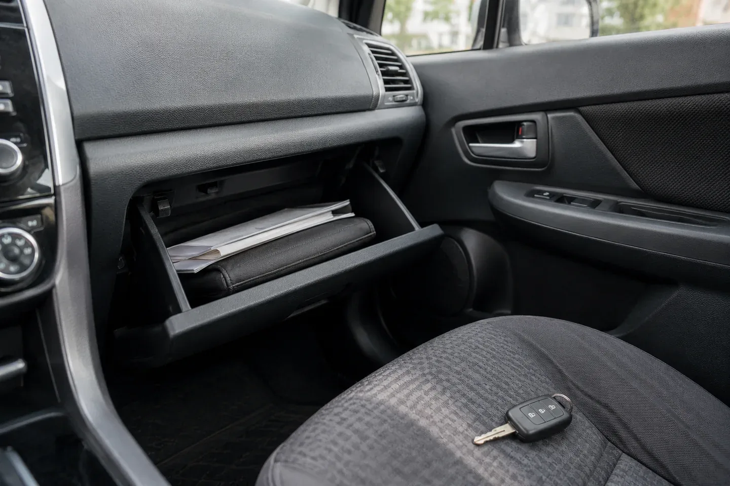 An open glove compartment containing a document wallet and vehicle paperwork.